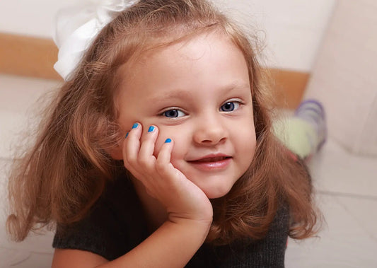 Petite fille souriante avec ongles peints en bleu