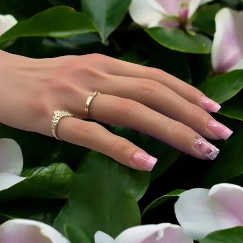 Main avec de jolis ongles rosés et fleurisé avec un décor de magnolias autour